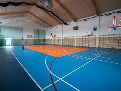 Zdjęcie przedstawiające salę gimnastyczną z boiskiem do siatkówki i koszykówki.
