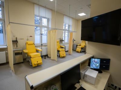 Zdjęcie przedstawiające gabinet medyczny z żółtymi fotelami zabiegowymi oddzielonymi zasłonami.